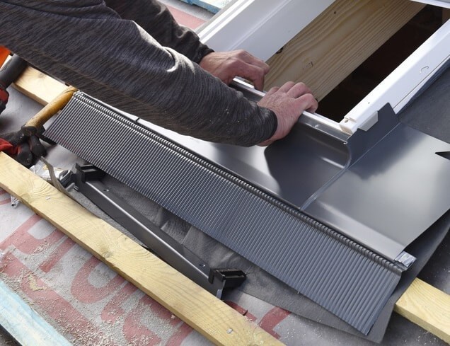 A piece of bottom element flashing underneath a roof window being installed