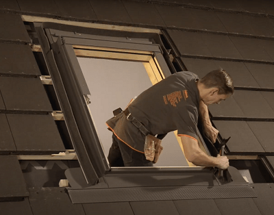 A roofer nailing side element of flashing onto a window
