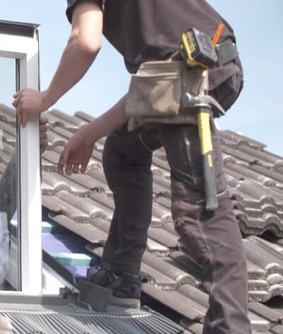Roofer installing a window with tools on his belt