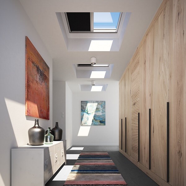 A hallway with three overhead roof windows half covered by blinds