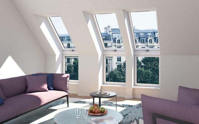 A living room with three tall roof windows showing a view of the city