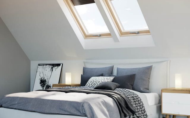 A bedroom with a pair of roof windows on the wall behind the bed