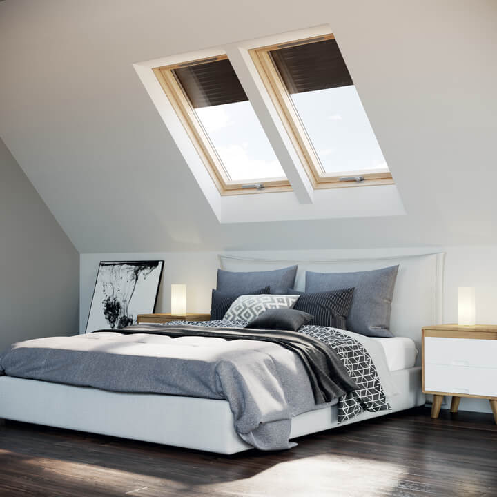 A bedroom with a pair of roof windows on the wall behind the bed