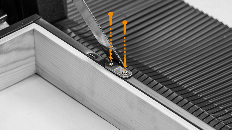 Two screws, highlighted in orange, being unscrewed into the fixture on the top of the skylight