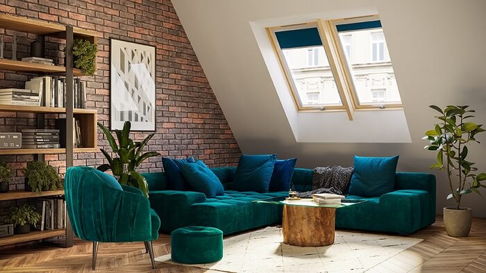 A blue corner sofa in a cosy attic room with a book on a small glass table