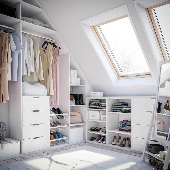 A white, well-lit room with lots of clothes storage including open wardrobes and shoe racks