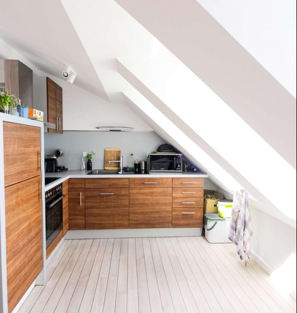 A small kitchen in a loft that features a wood design. Wooden and cupboards are the main features. Roof windows make the space brighter