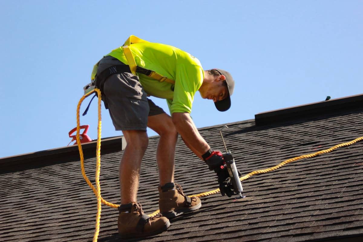 A roofer working on a roof with a caulking gun.