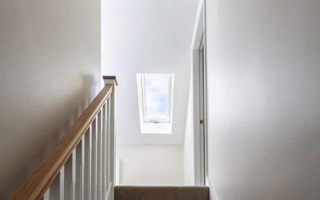 A pitched roof window placed at the top of a staircase.